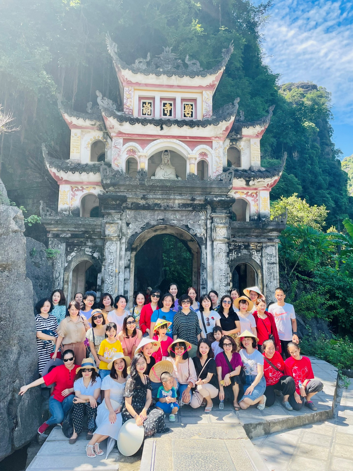 A group of people posing for a photo in front of a building

Description automatically generated